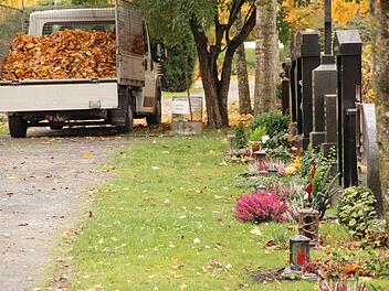 Wege und Grasflächen am Münnerstädter Friedhof werden vor Allerheiligen vom Herbstlaub befreit. Die Gräber sind geschmückt. Foto: H. Beudert