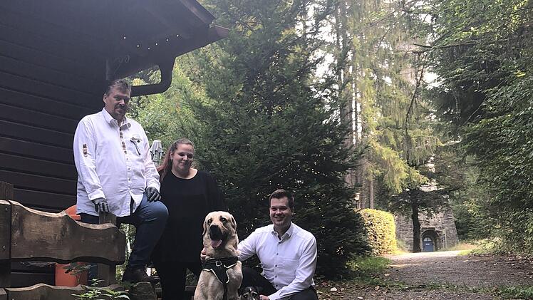 Neu auf der Arnoldhütte: Die Wirtsleute Hans-Jürgen und Michaela Ühlin mit Geschäftsführer Torsten Klein sowie den Hunden Ocean, ein vierjähriger Dogge-Labrador-Mischling, und Jamie-Oliver - ein neunjähriger Jack-Russell-Terrier. Hinten der Prinzregententurm, der im geplanten Märchenwald zum "Rapunzel-Turm" werden soll. Fotos: Christoph Böger