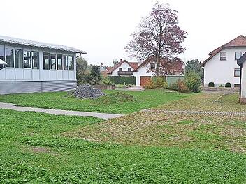 Diese Fläche zwischen bisherigem Feuerwehrhaus mit Schulungsraum (rechts) sowie neuem Feuerwehrhaus (links) wird 19 Parkplätze erhalten und dabei wird viel Grünfläche rundherum bis zur Rathausstraße (im Hintergrund) neu gestaltet.