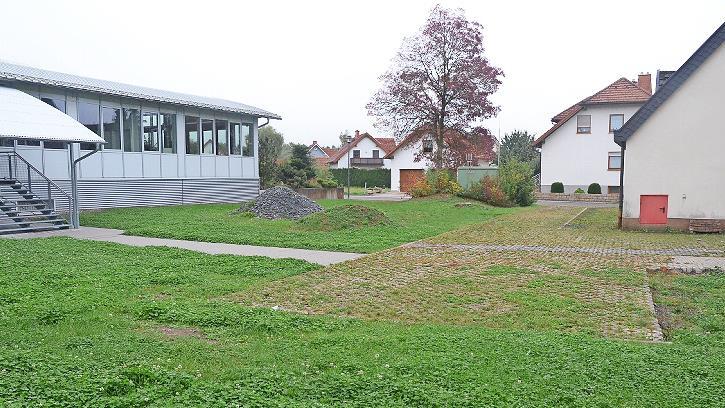 Diese Fläche zwischen bisherigem Feuerwehrhaus mit Schulungsraum (rechts) sowie neuem Feuerwehrhaus (links) wird 19 Parkplätze erhalten und dabei wird viel Grünfläche rundherum bis zur Rathausstraße (im Hintergrund) neu gestaltet.
