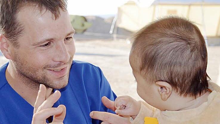 FAST-Mitarbeiter Sebastian Wetzel versorgt ein krankes  Kleinkind.
