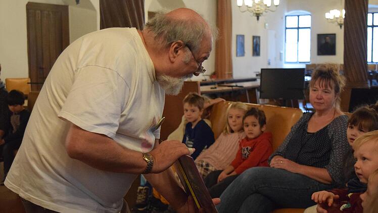 Die Kinder des Regenbogenkindergartens in Coburg lauschen im Rathaus den Geschichten von Thomas Mac Pfeifer  -  und schauen sich auch die bunten Bilder in seinen Büchern an. Foto: Daniela Pondelicek
