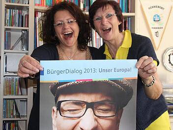 Michelle Görtler (links) und Herta Wächter, die beiden Mitarbeiterinnen der VHS Kronach, nehmen sich schon ein Beispiel an dem Mann auf dem Werbeplakat und reißen den Mund auf. Die Bürger können dies am 8. Mai tun.Foto: Corinna Igler