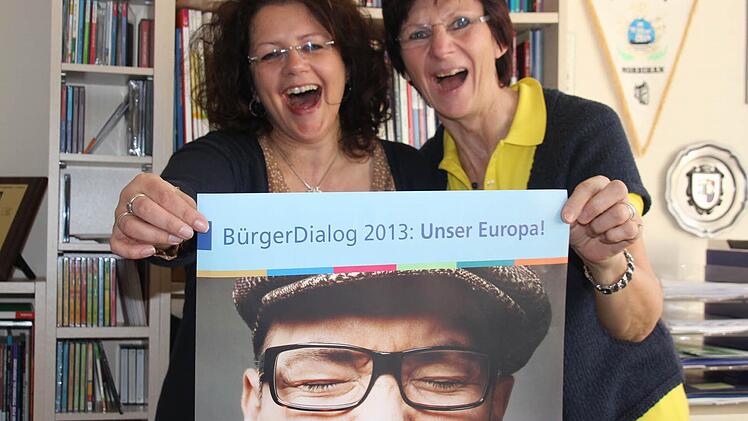Michelle Görtler (links) und Herta Wächter, die beiden Mitarbeiterinnen der VHS Kronach, nehmen sich schon ein Beispiel an dem Mann auf dem Werbeplakat und reißen den Mund auf. Die Bürger können dies am 8. Mai tun.Foto: Corinna Igler