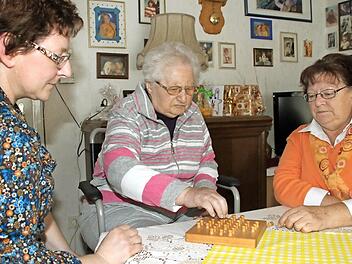 Spielerisch trainieren Sabine Schröder (links) und Evi Möhrlein mit ihrer Mutter Lydia Berger Gedächtnis und Reaktionsvermögen. Auch das ist Teil der intensiven Pflege und Betreuung in den eigenen vier Wänden. Foto: Dagmar Besand