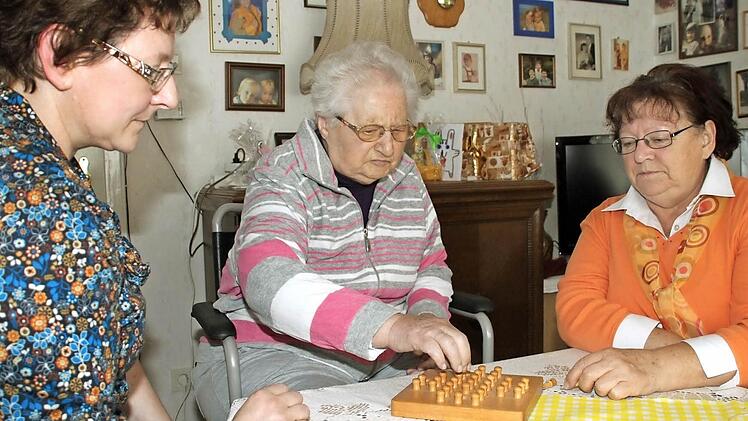 Spielerisch trainieren Sabine Schröder (links) und Evi Möhrlein mit ihrer Mutter Lydia Berger Gedächtnis und Reaktionsvermögen. Auch das ist Teil der intensiven Pflege und Betreuung in den eigenen vier Wänden. Foto: Dagmar Besand
