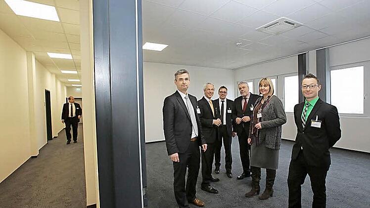 14 Meter lang ist jedes Modul und umfasst zwei Büroeinheiten mit dem Flur dazwischen (links erkennbar). Die Büros selbst fallen unterschiedlich groß aus, je nachdem, über wie viele Module sie sich erstrecken. Bei der Besichtigung (von links): Michael Müller, Leiter der Abteilung Kraftfahrzeugbetrieb, Wolfgang Weiler, Sprecher der HUK-Vorstände, Georg Ehmann, Bereichsleiter in der Kraftfahrtbetriebsabteilung, Oberbürgermeister Norbert Tessmer, Zweite Bürgermeisterin Birgit Weber und Alexander ...