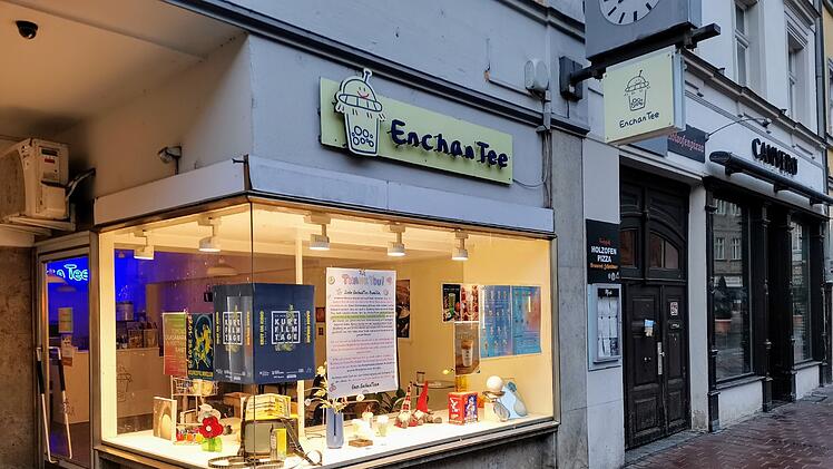 Ein Teeladen namens "EnchanTee" in Bambergs Innenstadt hat ein beleuchtetes Schaufenster mit Dekorationen. Ein Abschiedsbrief im Fenster deutet auf die baldige Schließung hin.