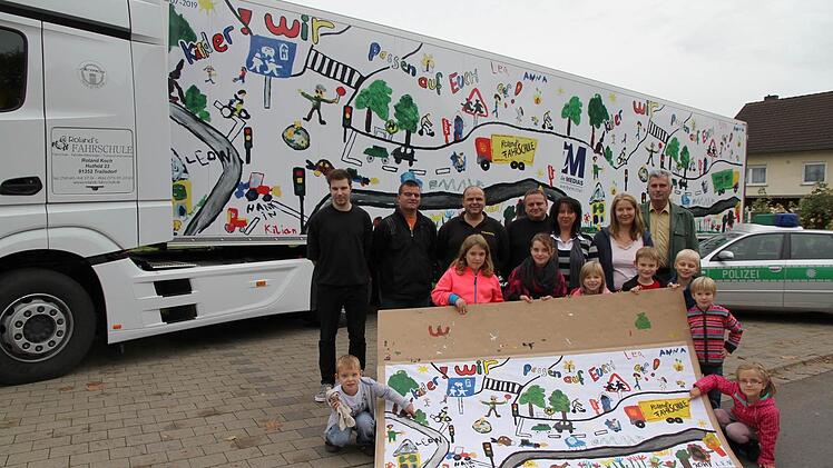 Die Kinder zeigen das Originalbild, das jetzt den Lkw-Auflieger ziert: "Kinder, wir passen auf Euch auf", so der Appell.  Foto: Erlwein