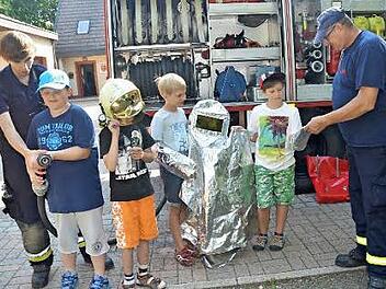 Georg Wunder (rechts) erklärt Adam, wie man den futuristisch wirkenden Hitzeschutz Poncho richtig anzieht, um dann vor der Brandhitze geschützt zu sein. Foto: Karl-Heinz Hofmann
