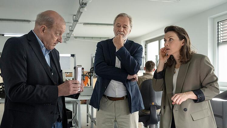 Simone Rupert (Kathrin von Steinburg) arbeitet in der Firma ihres Vaters (Gerd Silberbauer, Mitte) als Entwicklungschefin. Sie demonstriert Wilsberg (Leonard Lansink), der sich als Datenschutzbeauftragter der Stadt ausgibt, ihr neuestes Produkt: ein Sprachassistent in In-Ear-Form.