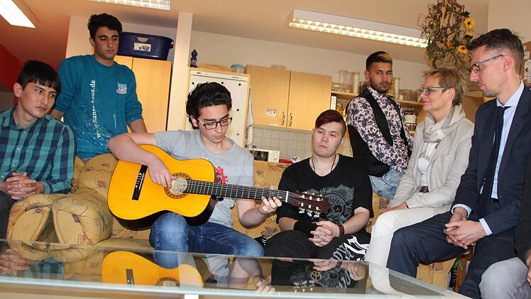 Der 17-jährige Mohammed aus Syrien zupft eine Melodie auf der Gitarre. Sabine Dittmar und Lars Castellucci lauschen den Klängen. Fast alle Jugendlichen auf dem Bild nutzten die Chance, sich mit den Politikern zu unterhalten. Foto: Ulrike Müller