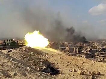 Wie hier in Syrien, kämpfen heutzutage Menschen gegen Menschen. Geht es nach den Militärs der Industrienationen, sollen bald Automaten das blutige Handwerk übernehmen. Die USA, Großbritannien, Israel - mehrere Länder arbeiten bereits an Killerrobotern, die "selbstständig Menschen töten" sollen.  Das von der staatlichen Nachrichtenagentur Sana zur Verfügung gestellte Videostandbild zeigt am 02.11.2017 in Deir as-Saur (Syrien) einen schießenden syrischen Panzer und Rauchwolken über der Stadt.  ...