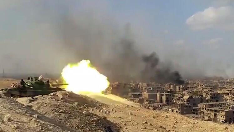 Wie hier in Syrien, kämpfen heutzutage Menschen gegen Menschen. Geht es nach den Militärs der Industrienationen, sollen bald Automaten das blutige Handwerk übernehmen. Die USA, Großbritannien, Israel - mehrere Länder arbeiten bereits an Killerrobotern, die "selbstständig Menschen töten" sollen.  Das von der staatlichen Nachrichtenagentur Sana zur Verfügung gestellte Videostandbild zeigt am 02.11.2017 in Deir as-Saur (Syrien) einen schießenden syrischen Panzer und Rauchwolken über der Stadt.  ...