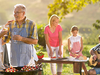 smiling grandparents drinking wine and enjoying picnic