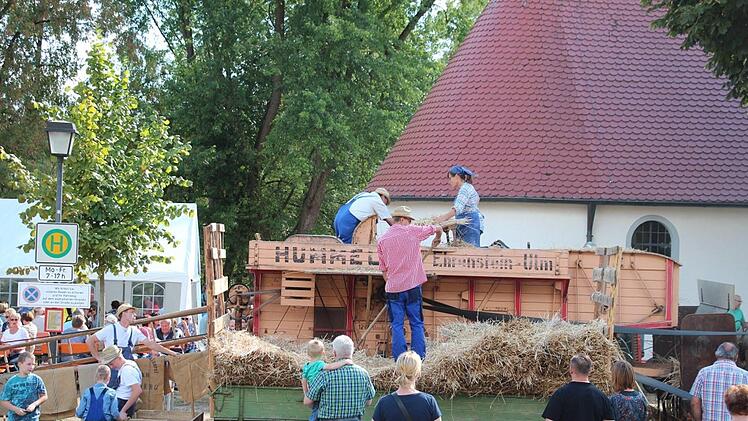 Tobias Pospischil wirft die Garben Georg Pornschlegel und Maria Schneider zu. Diese legen die &Auml;hren in die Maschine ein.