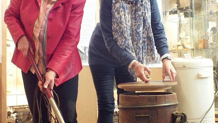 Brigitte Schieder mit Staubsauger und Jutta Triantafyllidis-Grimm am Butterfass