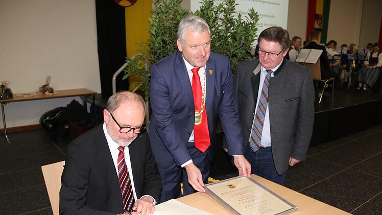Robert Herrmann trägt  sich in das goldene Buch der Stadt Ebern ein. Dies beobachten (von rechts) Staatssekretär Gerhard Eck und Bürgermeister Jürgen Hennemann.