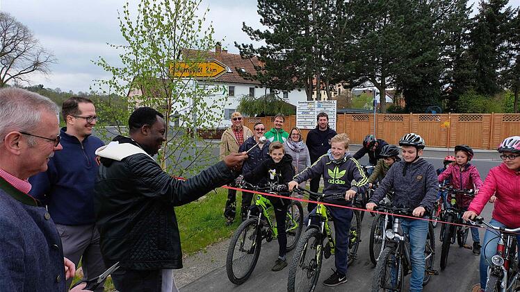Die Radler warten auf das Startsignal, nachdem Pfarrer Dr. Blaise Okpanachi den Segen für den neuen Geh- und Radweg erteilte.  Foto: Gerd Schaar