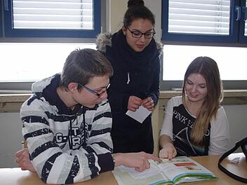 Nadja Jonak und Jonas Hümmer (von links, sitzend) geben Merve Bozat (stehend) einen Einblick in den Französisch-Unterricht in der Einführungsklasse.  Foto: Heike Schülein