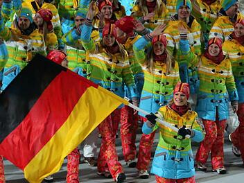 Deutsche Olympioniken in ihren Regenbogen-Mänteln bei der Eröffnungsfeier. Maria Höfl-Riesch (vorne, mit der Fahne) hat das schrille Outfit jedenfalls nicht geschadet: Bei der alpinen Kombination holt sie Gold.   Foto: dpa