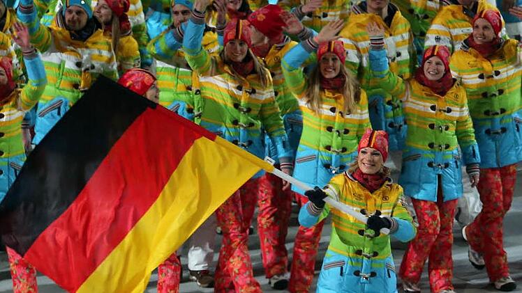 Deutsche Olympioniken in ihren Regenbogen-Mänteln bei der Eröffnungsfeier. Maria Höfl-Riesch (vorne, mit der Fahne) hat das schrille Outfit jedenfalls nicht geschadet: Bei der alpinen Kombination holt sie Gold.   Foto: dpa