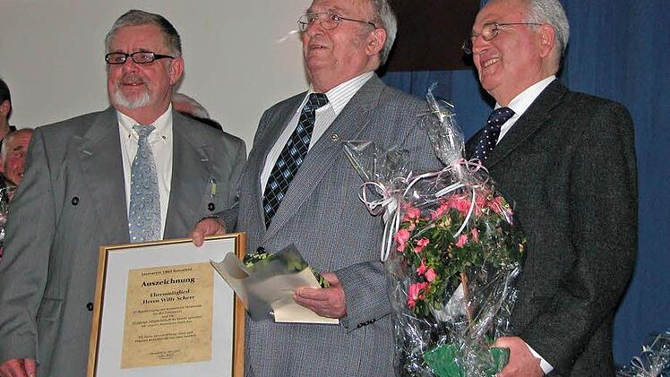 Jubiläumsurkunde, Präsent und Blumen nahm Willy Scherr aus der Hand des Vorsitzenden Friedrich Übelhack (links) und seinem Stellvertreter, Ehrenbürger Horst Knauer (rechts) entgegen.