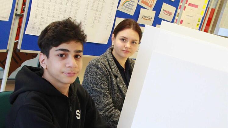 Salam Mushtaha und Melissa Steinert fühlen schon mal vor, wie es sein wird, wenn sie in zwei Wochen hinter dem Sichtschutz versteckt ihr Kreuzchen machen werden. Sie und ihre Klassenkameraden nehmen die Landtagswahl zum Anlass zu üben, wie man eigentlich wählt. Fotos: Carmen Schmitt