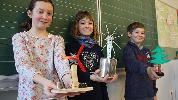 Marisa (von links), Nelly und Moritz zeigen ihre Werke: ein Ventilator, eine Eislöffelturbine und ein LED-Weihnachtsbaum.  Fotos: Robert Huger