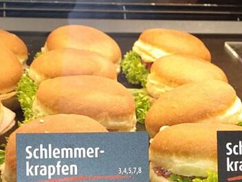 Schlemmekrapfen mit Salat und Aufschnitt in einer Theke. Ungewöhnliche Kombination sorgt für Aufmerksamkeit in einer Bäckerei.