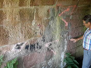 Bürgermeister Wilhelm Friedrich erklärt die sogenannten Bewegungsmarken in den Durchgängen. Mit ihnen wurde kontrolliert, ob das Bauwerk stabil ist oder sich im Laufe der Zeit verformt. Foto: Rolf Pralle