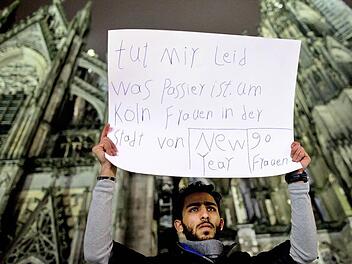 Ein Mann aus Syrien drückt mit einem Plakat vor dem Kölner Dom sein Mitgefühl aus.  Foto: Maja Hitij, dpa