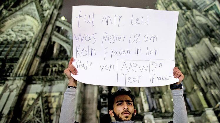 Ein Mann aus Syrien drückt mit einem Plakat vor dem Kölner Dom sein Mitgefühl aus.  Foto: Maja Hitij, dpa
