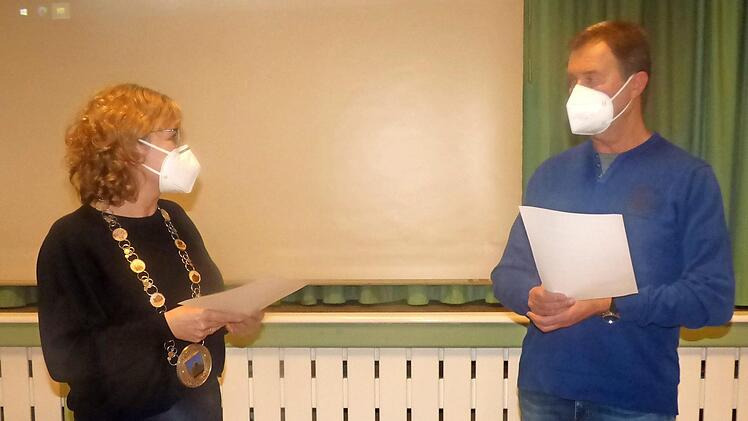 Bürgermeisterin Anja Gebhardt vereidigt den neuen Feldgeschworenen Helmut Pieger mit Maske und Corona-Abstand.
