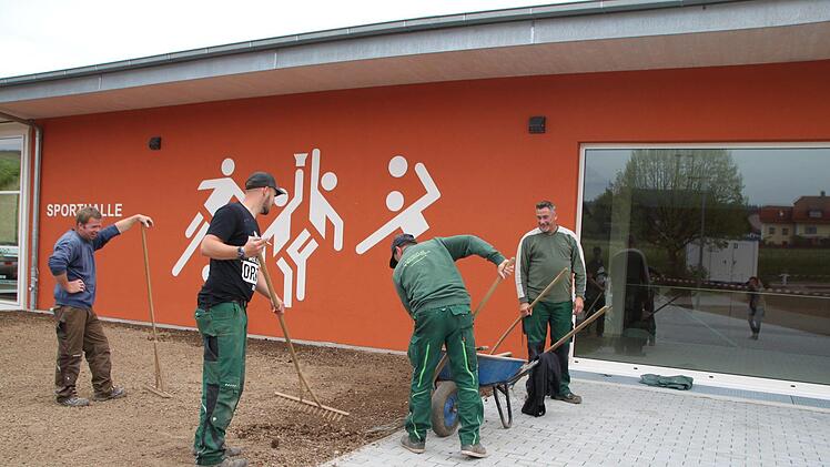 Gartenarbeiter gestalten die Außenanlagen vor der Turnhalle. Foto: Ulrike Müller