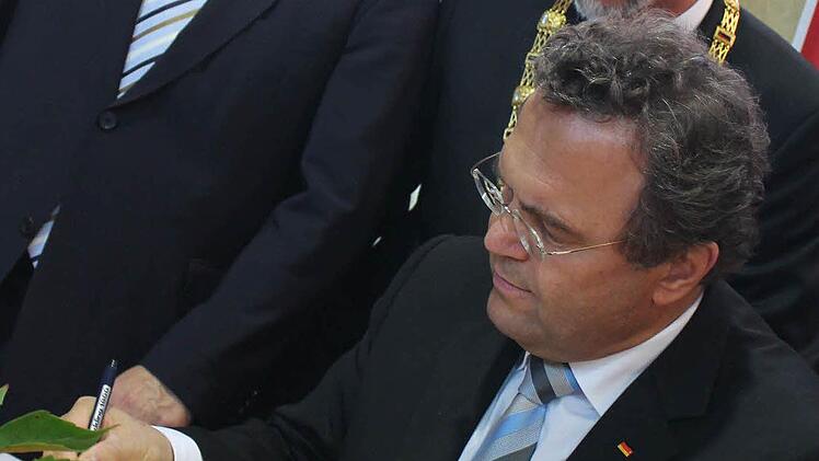 Hans-Peter Friedrich (vorne) trägt sich im Beisein von Thomas Bold (links) und Kay Blankenburg ins goldene Buch der Stadt ein. Foto: Benedikt Borst