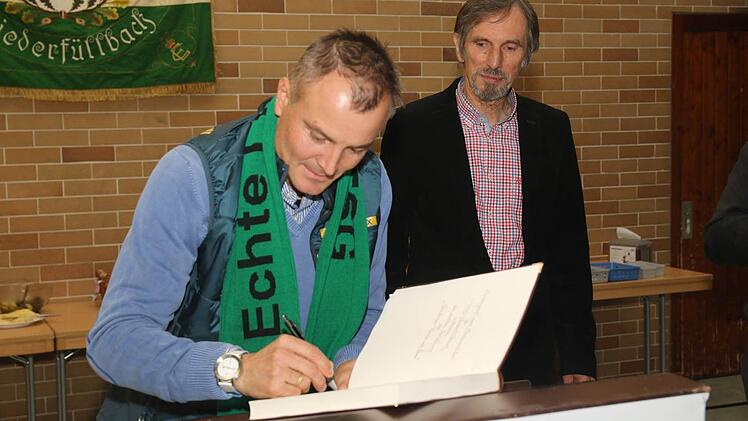 Bürgermeister Martin Rauscher schaut zu, wie sich Sven Fischer in das Goldene Buch der Gemeinde einträgt. Foto: Michael Stelzner
