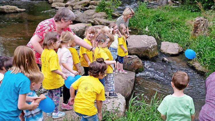 Die Kinder des Kindergartens St. Elisabeth durften ihre blauen Luftballons als symbolische Wassertropfen hinter dem Floß in die Thulba werfen.