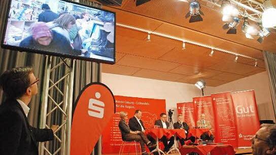 Andrang im Sozialkaufhaus als Einspieler zu Beginn des Regionentalks. Auf dem Podium (von links) Barbara Kammerscheid, Detlef Juranek, Moderator Thomas Apfel, Michael Busch und Jürgen W. Heike. Foto: nel