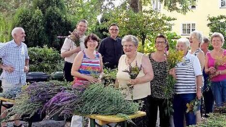 Norbert Schuhmann, Pfarrer Holger Fiedler und Pfarrer Jaroslaw (hinten von links) unterstützen die fleißigen Frauen beim Binden der Kräuterbüschel.  Foto: pr