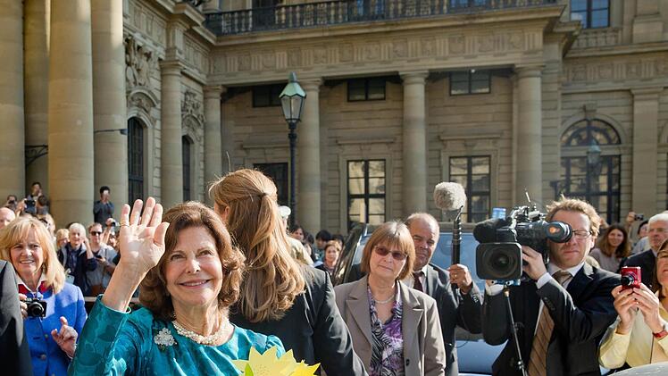 Königin Silvia von Schweden winkt vor der Residenz in Würzburg im Rahmen einer von ihrer Stiftung Childhood organisierten Fachtagung den Zuschauern zu. Foto: Daniel Karmann/dpa