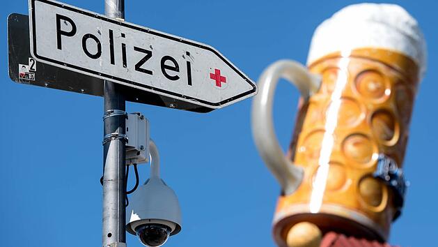 Eine Videokamera und ein Hinweisschild auf die Polizei h&auml;ngen in M&uuml;nchen dem Oktoberfestgel&auml;nde an einer Stra&szlig;enlaterne. Da sich auch auf dem weltgr&ouml;&szlig;ten Volksfest immer wieder sexuelle &Uuml;bergriffe ereignen, hat die Polizei die Sicherheitsvorkehrungen verst&auml;rkt. Foto: Sven Hoppe, dpa