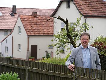 Roland Brönner am Gartenzaun mit der Straßenkulisse von Neuwirtshaus im RückenFoto: Arkadius Guzy