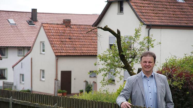 Roland Brönner am Gartenzaun mit der Straßenkulisse von Neuwirtshaus im RückenFoto: Arkadius Guzy