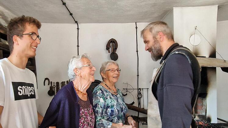 Helene Hofmann (Schwiegertochter von Eugen Hofmann) und Zita Dechert (Tochter von Eugen Hofmann) lassen sich von Schmied David Rosenberg die Schmiede zeigen. Mit im Bild links der  Urenkel von Eugen Hofmann Alexander Hofmann.