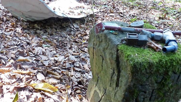 Zwei kleine Gedenksteine an der Absturzstelle erinnern an das Unglück. Ein Stein trägt sechs Kreuze, der andere Stein (nicht im Bild) die Namen Verunglückter. Auf dem Stein und daneben liegen Wrackteile.  Foto: ks