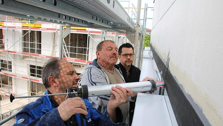 Nysret Imrihari (von links) und Reiner Stühler von der Firma "Haga" dichten nach dem Einbau der mehr als 200 Fenster die Fassade des Landratsamtes ab. Architekt Stephan Scharf betreut die Arbeiten. Foto: Ralf Ruppert