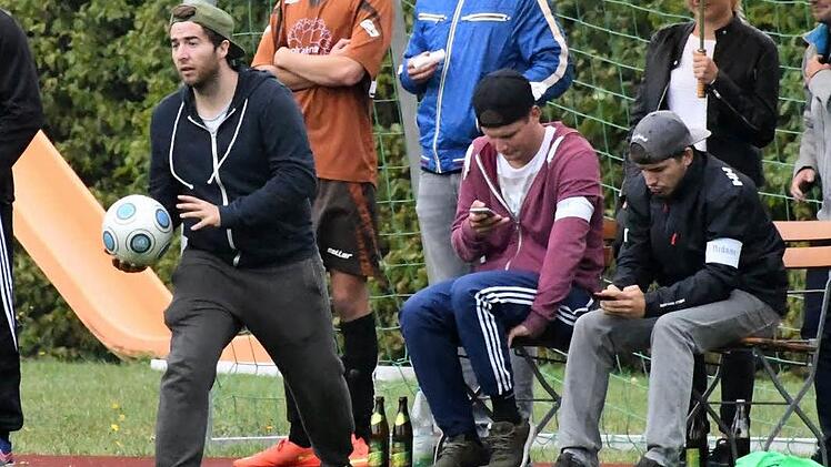 Zum Gl&uuml;ck nahmen die Smartphones der Zuschauer in Rottershausen keinen Schaden, als der Ball zur Seitenlinie hinaus flog. Der Inhalt der Displays scheint jedenfalls interessanter zu sein als das Spiel, das 5:2 f&uuml;r den Gast aus Steinach ausging. Foto: Hopf
