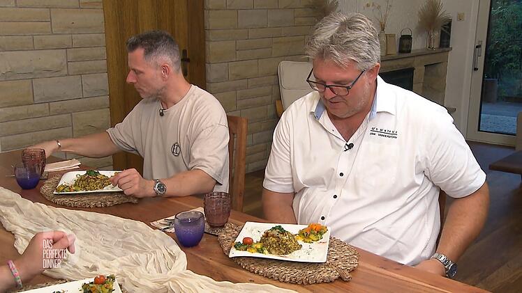 Andreas (r.) begutachtet die vegetarische Hauptspeise aus Bulgur und Linsen.