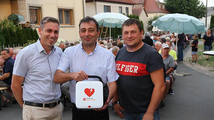 Die beiden Vorsitzenden der Dorfgemeinschaft, Georg Kratz und sein Stellvertreter Daniel Fleischmann, und Bürgermeister Torsten Gunselmann (l.) bei der Übergabe des Defibrillators Foto: Mathias Erlwein